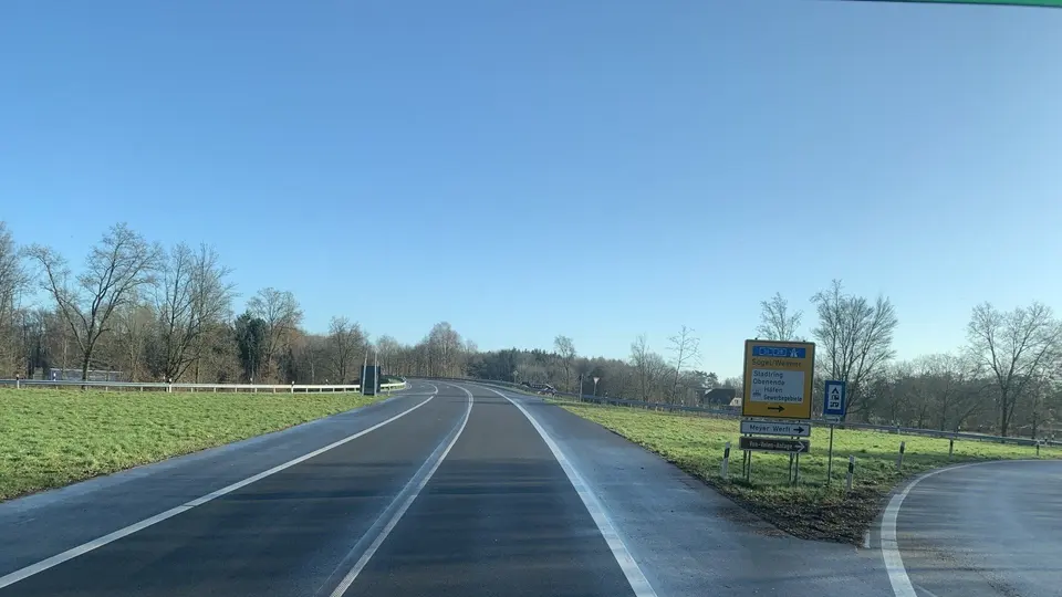 Offene Emsland-Landstraße mit Fahrbahnmarkierung und blauem Himmel