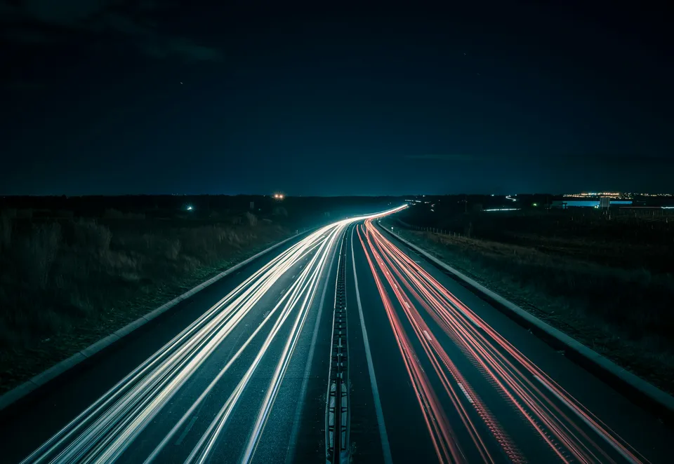 Autobahn bei Nacht mit den Lichtspuren vorbeifahrender Autos
