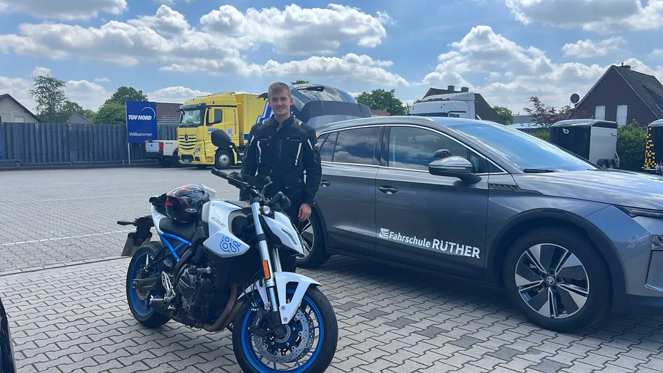 Fahrschüler mit Motorrad neben einem Fahrschulwagen der Fahrschule Rüther auf dem Hof
