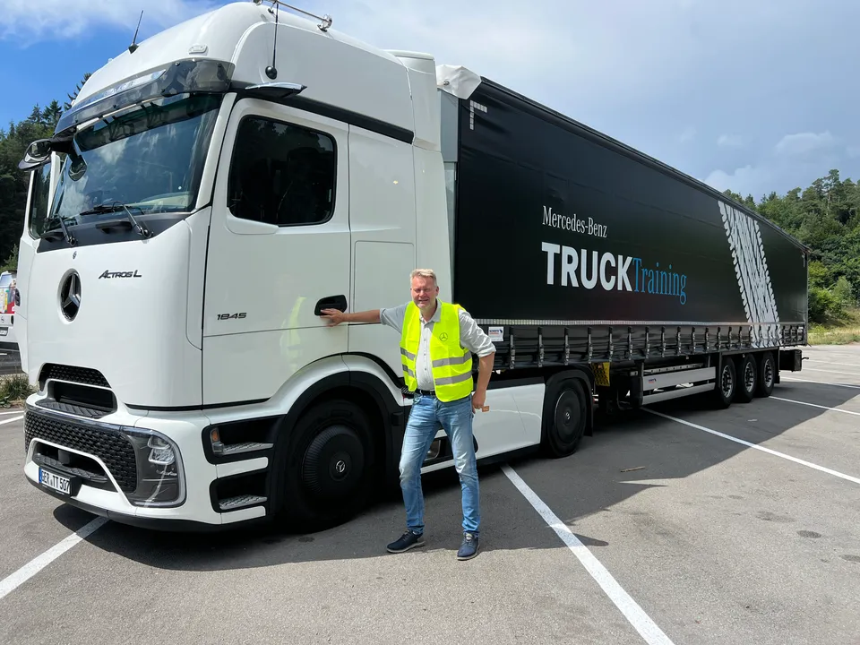 Fahrlehrer vor einem Mercedes-Benz-Truck-Training-Anhänger